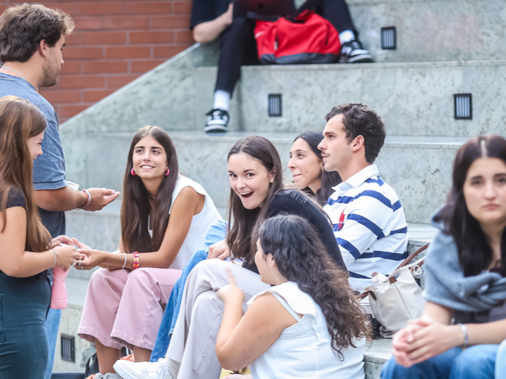 Zdjęcie przedstawiające roześmianych studentów siedzących na schodach.