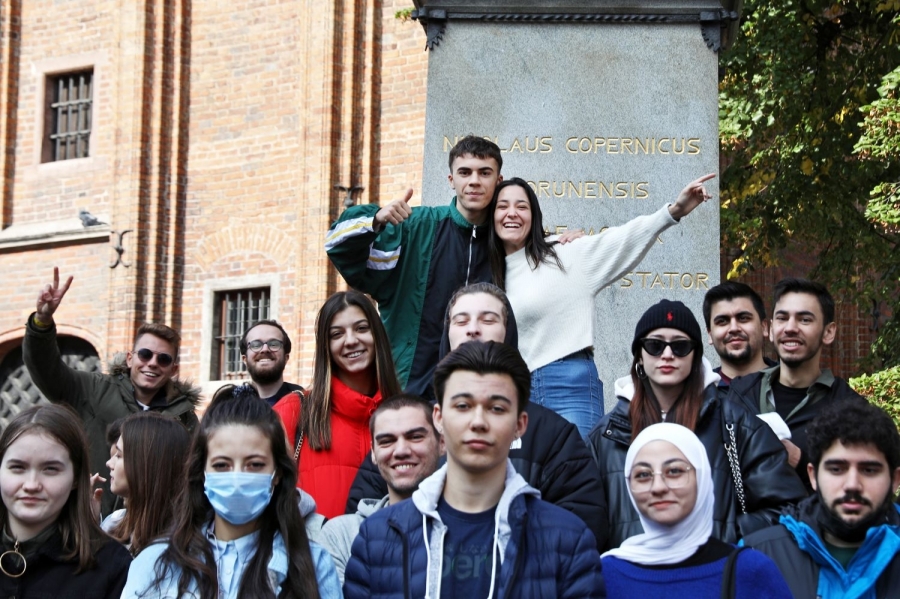 Studenci programu Erasmus+ na tle pomnika Mikołaja Kopernika w Toruniu.