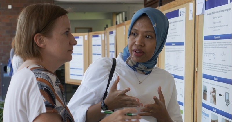 two women standing in front of a scientific poster, the student is explaining her results to a a jury member