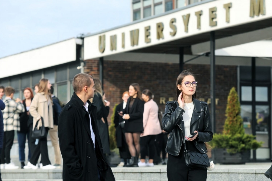 Grupa osób stojących przed budynkiem Uniwersytetu