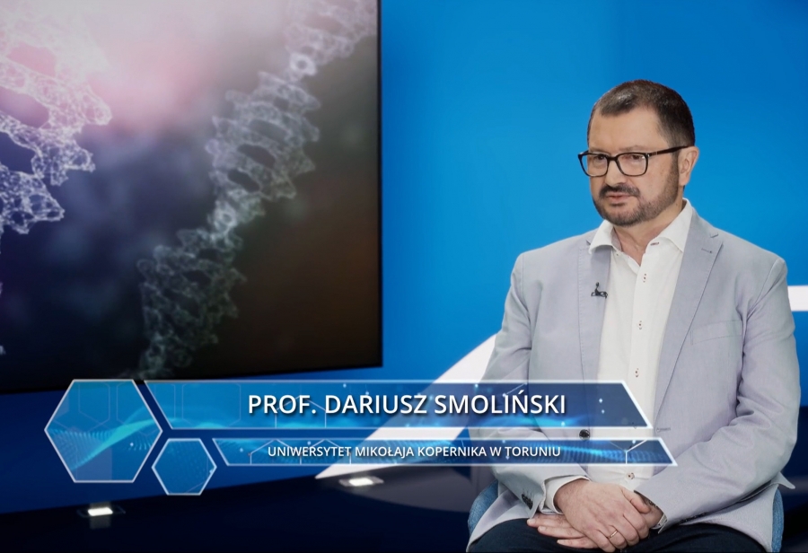 dr hab. Dariusz Smoliński, prof. UMK w studiu redakcyjnym na tle stylizowanej planszy z DNA