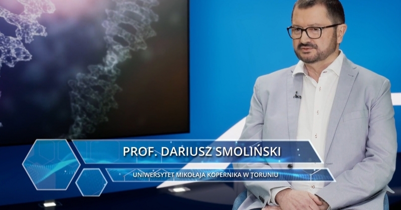 dr hab. Dariusz Smoliński, prof. UMK w studiu redakcyjnym na tle stylizowanej planszy z DNA