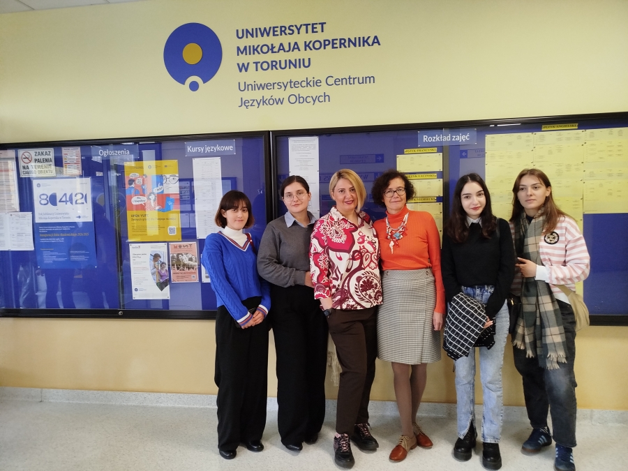 In the foreground, students and lecturers of English are standing in a row, smiling. In the background, above the heads of the students, there is an inscription: University Centre for Foreign Languages